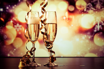two champagne glasses with ribbons against holiday lights and fireworks - New Year celebrations