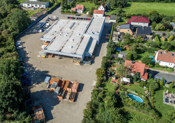 Large industrial hall next to a residential area with detached houses and gardens, aerial view