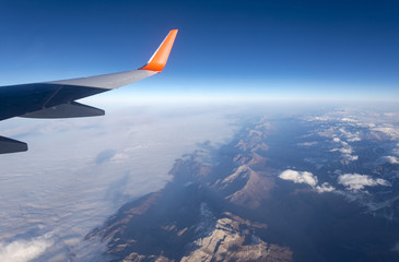 Fototapeta premium Flight over mountains and clouds, view from the plane