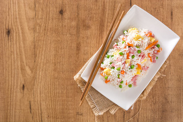 Chinese fried rice with vegetables and omelette on wooden table.Top view
