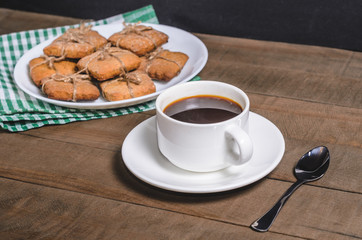 Black coffee in a white cup on a green napkin and homemade cookies.