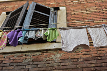 Window and clothes hanging. Wall facade old house. An old mansion, ancient brick wall. Outside there are clothes hanging on a wire. Typical Italian scene
