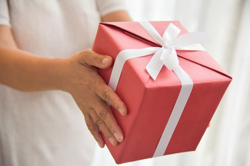 Close up on hands. Asian elderly woman holding on red gift box. Birthday, Christmas and New year.
