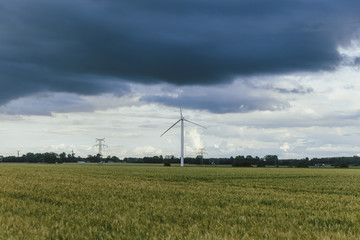 Fototapeta na wymiar Wind turbines for electrical power generation in green agricultural fields in Normandy, France. Renewable energy sources, industrial agriculture concept. Environment friendly energy production