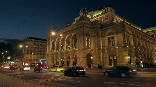 Static wide night shot of traffic passing in front of the Vienna Opera House on Opernring. Taken in September as the city lights are coming on