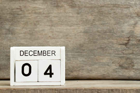 White block calendar present date 4 and month December on wood background