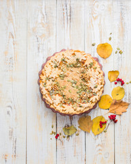 Autumn background with pumpkin pie, hot tea, yellowed leaves, book and rug. Perfect sunny autumn. A wooden light white autumn background for you. Copy Space. Place for text. Flat lay, top view