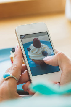 Woman takes a picture of cupcake on the plate