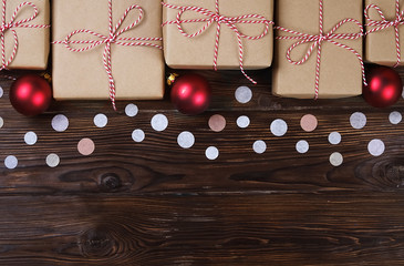 Lots of gift boxes on wooden background with confetti. Stylish presents in craft paper decorated with striped red and white ribbon bows. Christmas and winter holidays concept, top view, flat lay