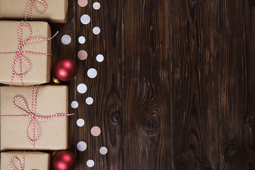 Lots of gift boxes on wooden background with confetti. Stylish presents in craft paper decorated with striped red and white ribbon bows. Christmas and winter holidays concept, top view, flat lay