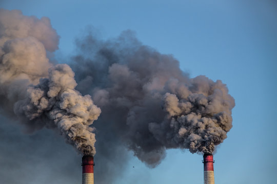 industrial chimneys with heavy smoke causing pollution on the blue sky background