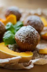 Tasty homemade muffins with powdered sugar decoration and 	pumpkin on the white plate on the wooden table