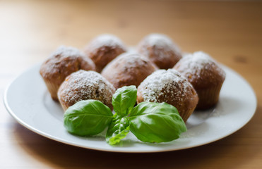 Tasty homemade muffins with powdered sugar decoration on the white plate on the wooden table