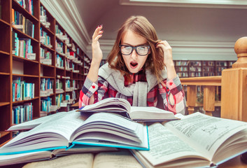 Shocked casual stylish student girl wears glasses studying hard with books in the library, education concept