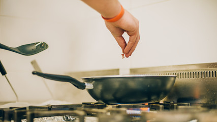 Chef cook prepares meal on frying pan in the kitchen