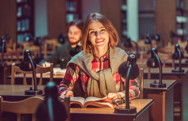 Portrait of two successful students casual stylish, boy and girl in library reading hall, evening time, education concept