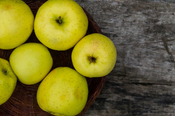 Ripe green apples in a basket on rustic wooden table
