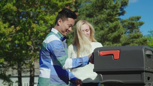 A young couple takes a letter from a mailbox. Emotionally rejoice