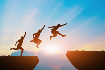 Men jump cliff sun light over silhouette 