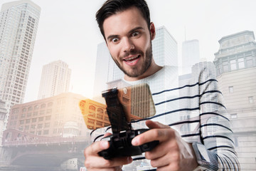 Emotional player. Positive excited young man looking attentively at the screen of his smart phone while playing a funny game © Viacheslav Yakobchuk