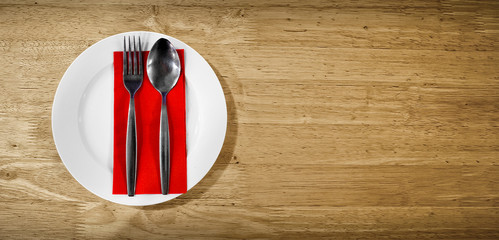 Pair of Silver Spoon and Fork on a Red Napkin on a Wooden Surface