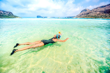 Fototapeta na wymiar Portrait of attractive girl wearing swimsuit and snorkling in clear ocean water