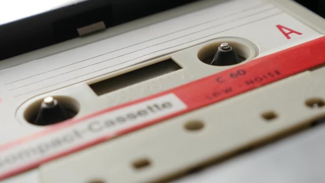 Shallow DOF audio tape player supply spindle footage - Retro cassette in casettophone close-up