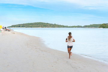 Fototapeta na wymiar Healthy woman running on beach at Koh Samui island morning.