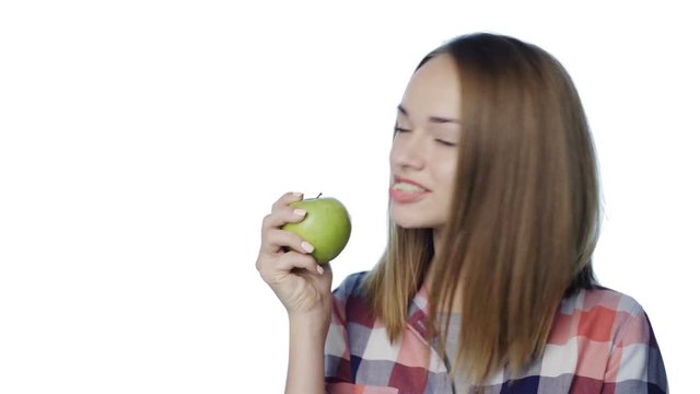 Closeup of smiling girl telling yam and biting big green apple and giggling