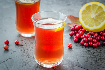 Hot fall tea with lemon and berries on dark concrete background. Selective focus, close up, copy space.