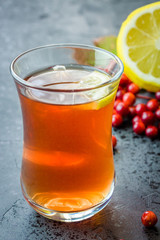 Autumn hot tea with lemon and berries on dark slate background. Selective focus, close up, copy space.