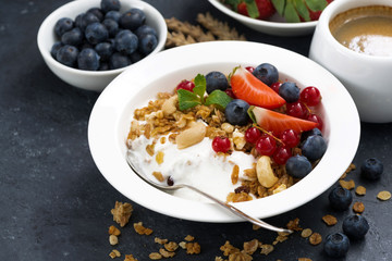 muesli with fresh berries, yogurt and coffee for breakfast on a dark background
