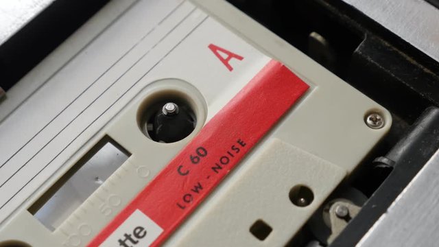 Music archives playing from cassette in casettophone close-up footage - Shallow DOF audio tape player supply spindle