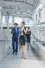 Professional business team using smartphone talk business project while walking forward confidently in cityscape background