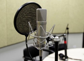 Professional condenser studio microphone over the musician blurred background and audio mixer,...