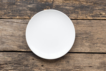 White plate is empty on old wooden floor.