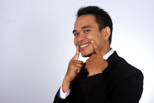 Asian businessman making fake smile with his fingers.