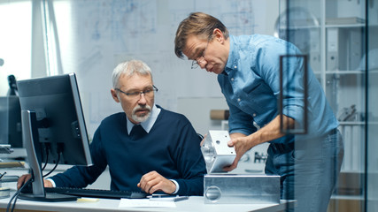 Two Senior Engineers Discuss Important Technical Component. Both are Experienced and Wise. Their Office Looks Modern and Bright.