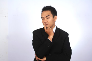 Asian businessman thinking while put the finger on the mouth
