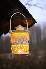 Decorative lantern with burning candle in autumn park at evening.