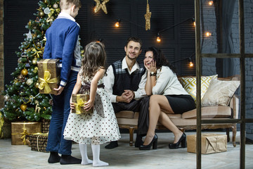 Fototapeta premium Beautiful happy family mother, father, son, and daughter to celebrate Christmas and new year together at home
