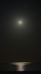 Aufnahme des Vollmond über dem Meer bei Nacht mit intensiver Speigelung im Wasser bei wolkenlosem...
