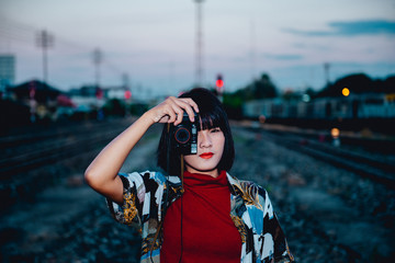 Portrait of asian hipster girl on sunset at railway vintage style,Grain and noise has been added to make effect of photographic film.