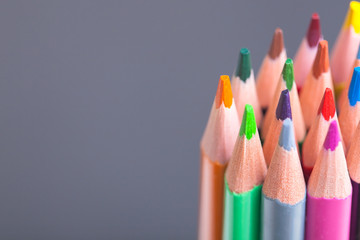 The sharp tips of the pencils. Bright colored pencils. Colored pencils on grey background with selective focus