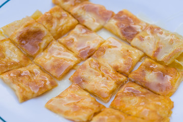 Roti bread topped with milk on white plate.