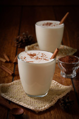 Eggnog houmemade with cinnamon and kakao for Christmas and winter holidays or wooden broun backgrounds