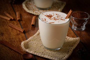 Eggnog houmemade with cinnamon and kakao for Christmas and winter holidays or wooden broun backgrounds