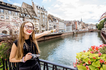 Fototapeta na wymiar Young woman tourist standing with photo camera on the old bridge over water canal traveling in Strasbourg city, France