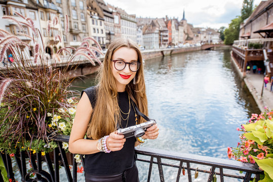Young woman tourist standing with photo camera on the old bridge over water canal traveling in Strasbourg city, France
