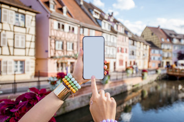 Naklejka premium Woman holding phone on the old buildings background in Colmar village in Alsace in north-eastern France